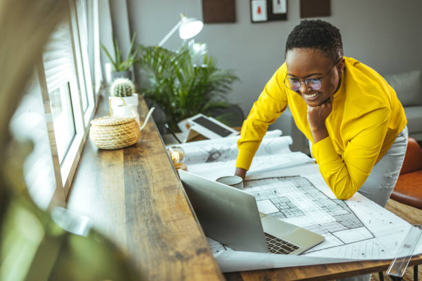 istock Smiling black female architect studies plans in an open plan office 1366407658