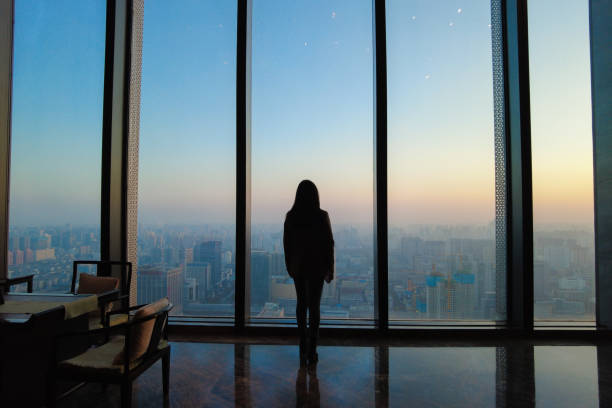 Businesswoman looking through office window at sunset