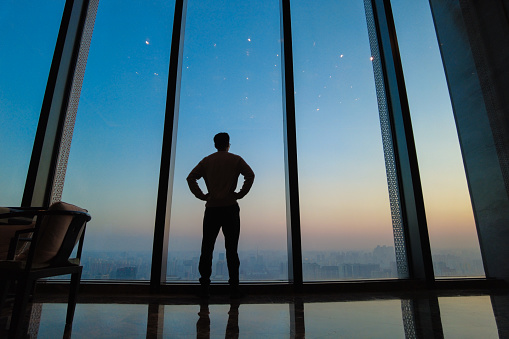 Young man  looking city skyline standing by office window