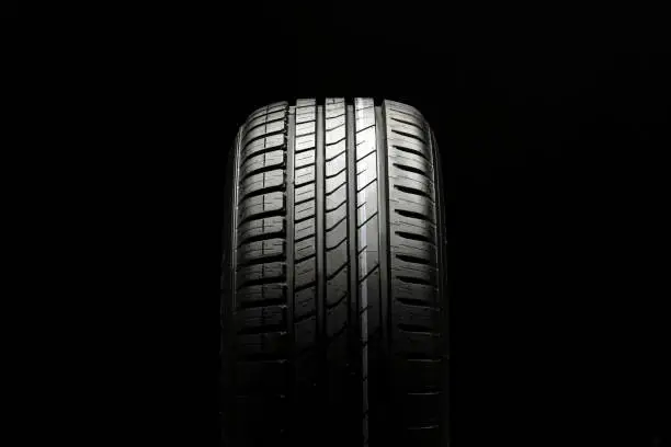 Photo of beautiful new summer tire on a black background. summer protector against aquaplaning and fuel economy