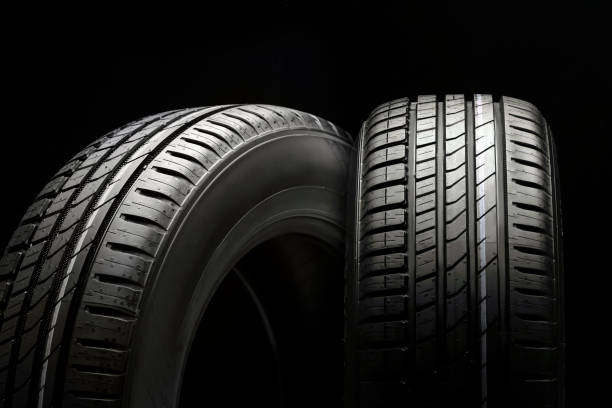 new beautiful tires on a black background, two summer car wheels with a modern tread. stock photo