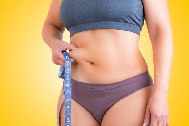 frau, die ihr taillenband zusammendrückt - overweight women body abdomen stock-fotos und bilder