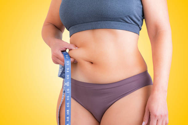 woman squeezing her waist holding tape measure - overweight women body abdomen imagens e fotografias de stock