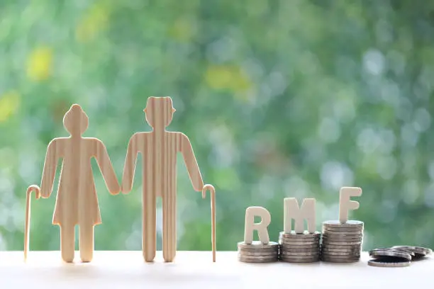 RMF - Retirement Mutual Fund, Love couple senior with RMF word on stack of coins money on natural green background, Save money for prepare in future and pension retirement concept