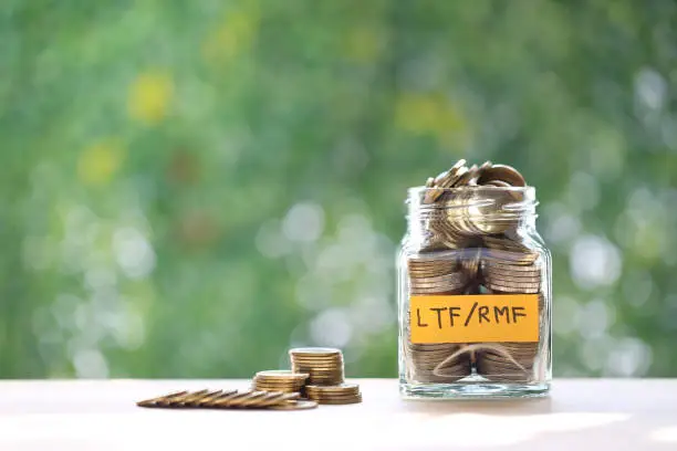 RMF - Retirement Mutual Fund, Stack of coins money in glass bottle on green background, Save money for prepare in future and pension retirement concept