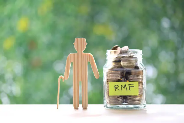 RMF - Retirement Mutual Fund, Senior man with RMF word and stack of coins money in glass bottle on natural green background, Save money for prepare in future and pension retirement concept