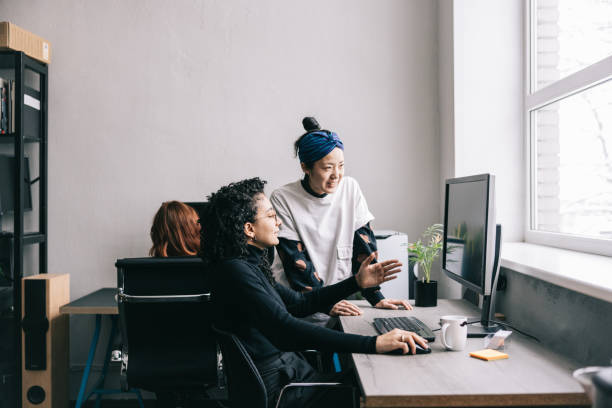 donna giapponese che aiuta il suo collega - programmatore di computer foto e immagini stock