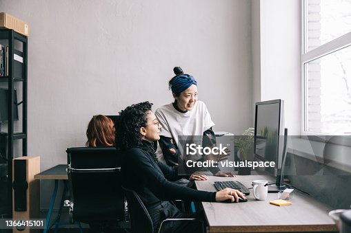 istock Japanese woman helping her colleague 1366415101