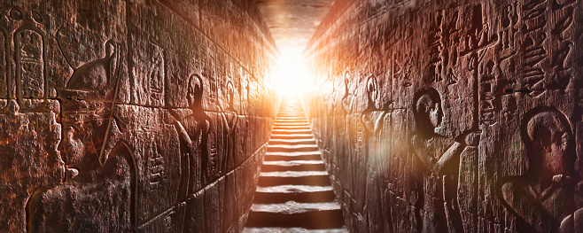 Egipto Templo de Edfu, Asuán. Pasaje flanqueado por dos paredes brillantes llenas de jeroglíficos egipcios, iluminado por una cálida luz de fondo naranja de una puerta photo