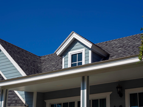 White vintage windows, little room decoration on the roof of the big wooden house pastel green color on blue sky background, view from outside.