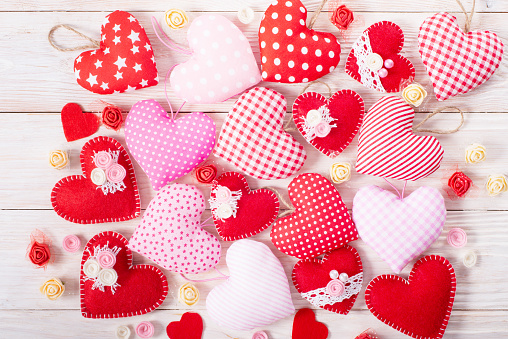 Sewed handmade fabric hearts for valentine day on white wooden background