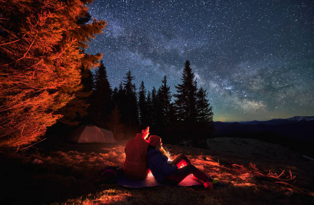 istock Pleasant rest of two hikers under open starry sky. 1366419133