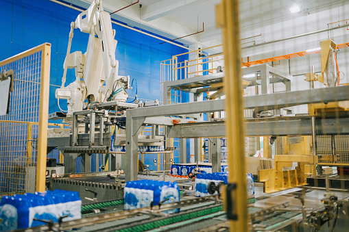 Robotic arm handling Wrapped Mineral water carton at finishing line Factory production line  on conveyor belt to packing in carton at loading bay