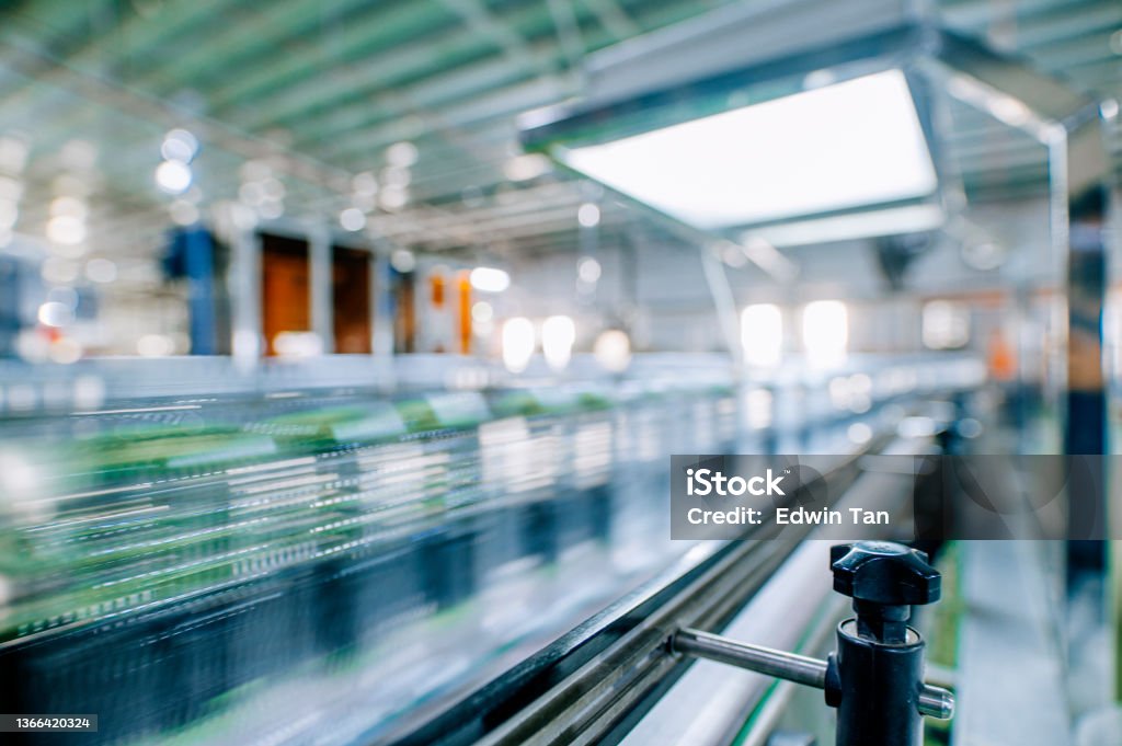 motion blurred fast moving water bottles at Mineral water Factory production line at finishing line in a row moving queuing for labelling packing Factory Stock Photo