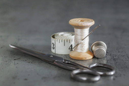 Various accessories for needlework. A set of sewing tools, spools of thread, fabrics, scissors and a thimble on an old surface. Retro style\