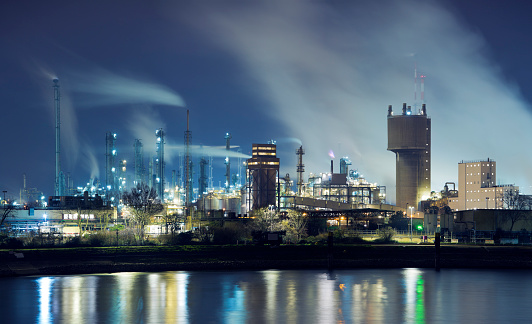 Illuminated petrochemical industry factory by a river at night