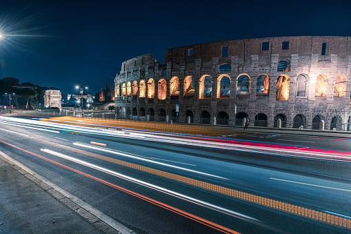 Colosseum at night Rome Italy with long exposure lights. Fast-moving traffic, bus cars.