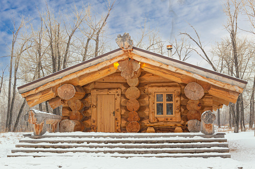 Fairytale wooden house made of giant logs in a winter snowy forest. Hut built of logs