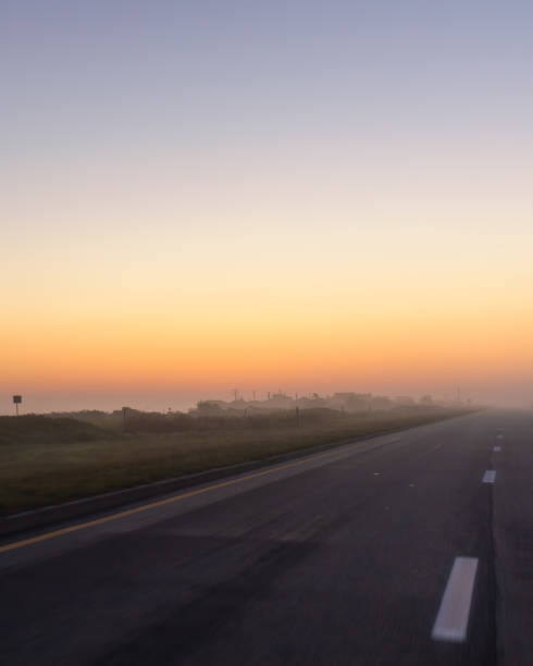 istock Empty road leading towards a hazy glowing morning sunrise 1366429231