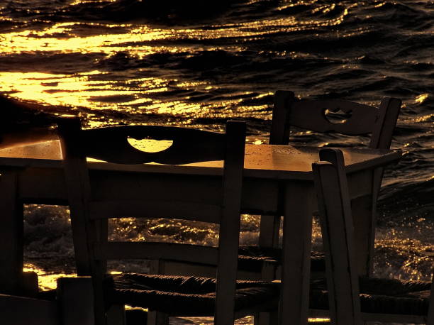 Wooden restaurant chairs and table by the sea on an autumn sunset in Mykonos, Cyclades, Greece