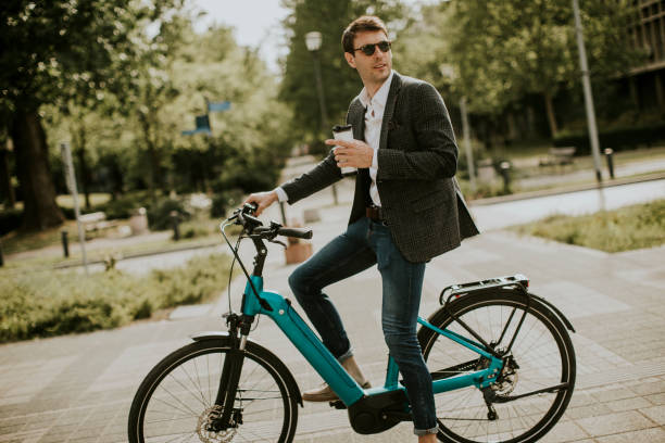 Young businessman on the ebike with takeaway coffee cup stock photo