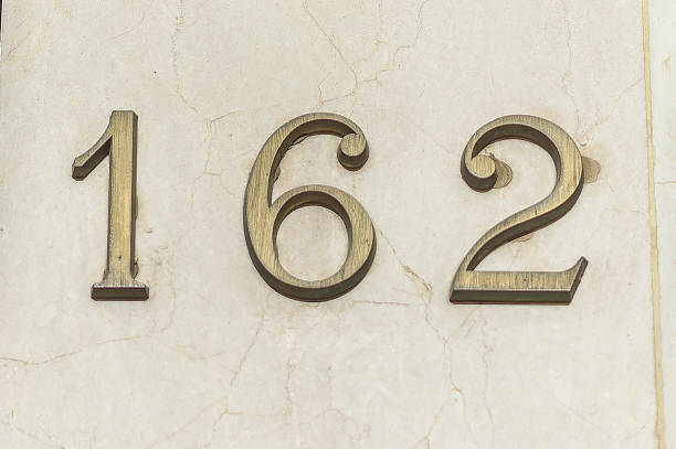 Bronze house number one hundred and sixty-two on a marble wall.