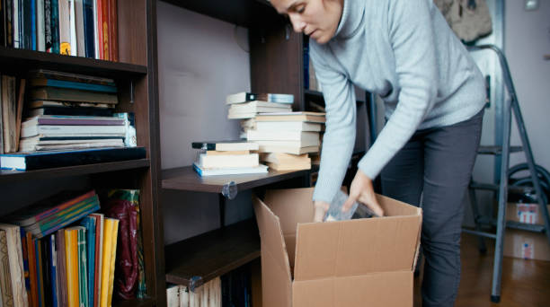 istock Packing books in cardboard boxes. Moving out. 1366442778