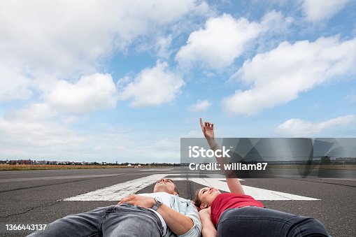 istock Happy couple on airport runway with plane landing 1366443137