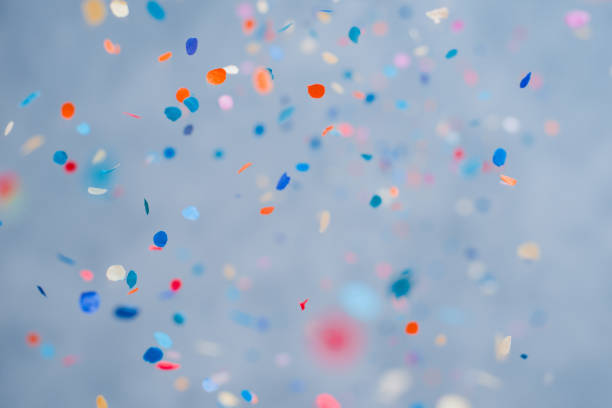 colorido confeti cayendo en unas vacaciones sobre un fondo azul - fiestas y celebraciones fotografías e imágenes de stock