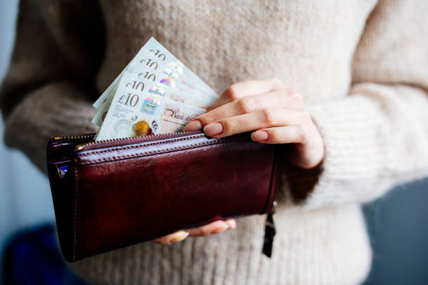 woman holding british pound - british pounds imagens e fotografias de stock