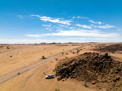 Dirt road meandering through expansive desert landscape with distant mountain range in Namibia, Luderitz