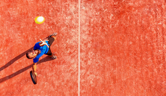 Top view of a professional paddle tennis player who is going to hit the ball during a padel match. The ball is very close to the camera.