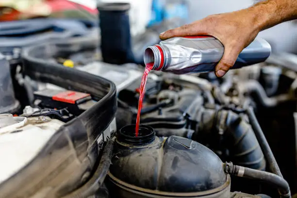 Photo of A Man is Filling the Water Tank on Car with Antifreeze.