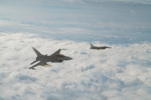 F-16 Jet fighters flying over clouds.