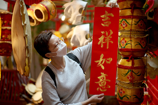 An Asian woman is showing Chinese calligraphy 'Ji Xiang Ru Yi' (Abundance of Good Luck) for Chinese New Year celebration.