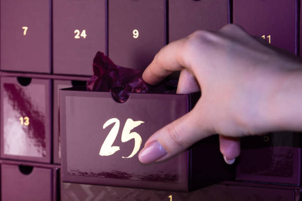 istock A woman's hand opens cell number 25 in the advent calendar. A gift wrapped inside a purple advent calendar. A Christmas gift. 1366452949