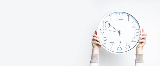 istock Female hands holding a large white watch on a light background. Banner. 1366454300