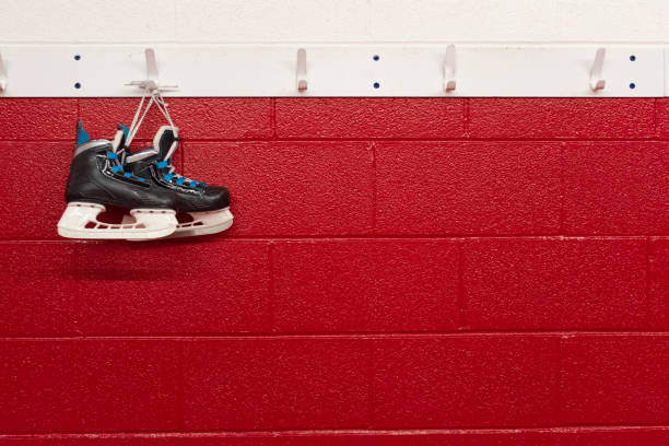 patins de hóquei pendurados sobre parede vermelha no vestiário com espaço de cópia - ice hockey ice team canada - fotografias e filmes do acervo