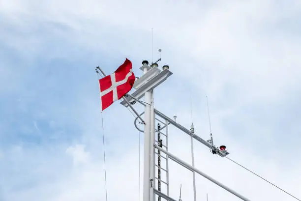 view of the danish flag waving in the wind on a mast of a ferry. view from below to the sky. Esbjerg, Jutland, Denmark