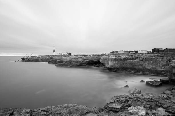 Souter Lighthouse south of the Tyne seen from Tynemouth with the sun setting behind the headland.