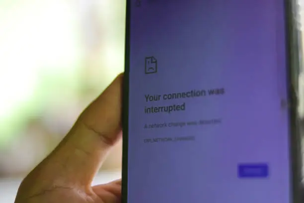 Hand holding phone with your connection was interrupted text. No connection and rural area without internet concept