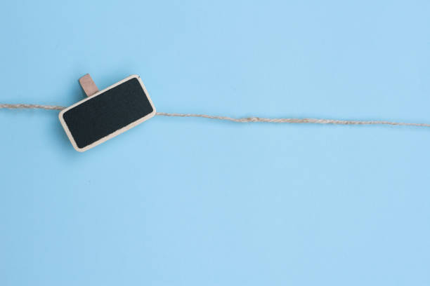 istock A blank black board for note attached to a rope on blue background. space for text 1366467439