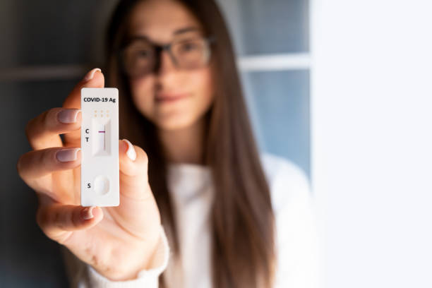 istock Woman's hand holding a negative self home test with negative result. Corona virus - Covid-19 rapid test. Young teenager girl. 1366469162
