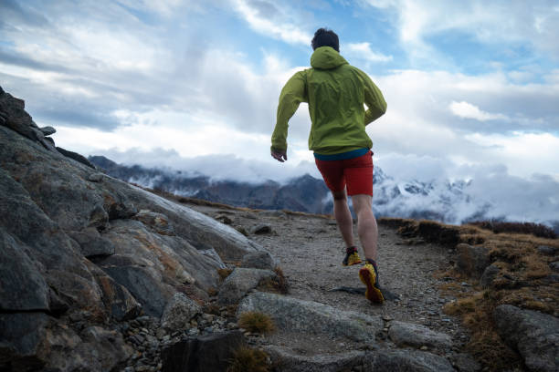 trail runner bounds up mountain trail - journey footpath exercising effort imagens e fotografias de stock