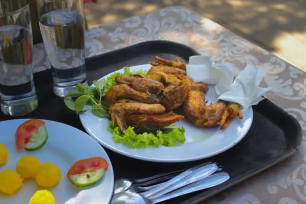 Ayam Bekakak or Grilled Whole Chicken with fresh vegetables on white plates ready to eat. Pabetot Bakakak is one of the Sundanese wedding traditions as a symbol of the sustenance that will be obtained