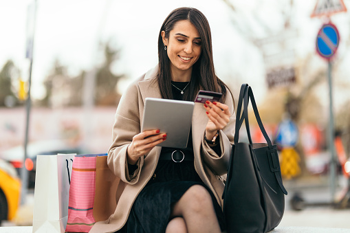 Young woman shopping with digital tablet outside