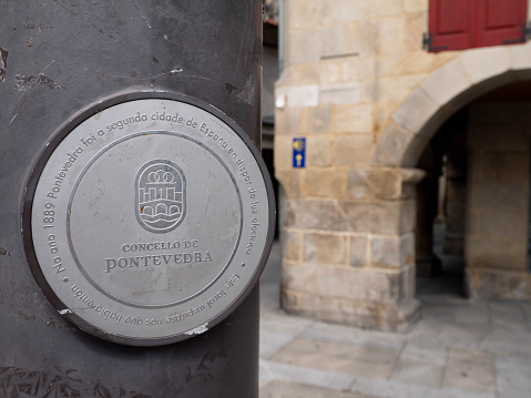 Pontevedra, Spain - july 25, 2021: Message in gallego language at the street lantern mast that Pontevedra is a second city in Spain where electrical street lighting was introduced in 1889