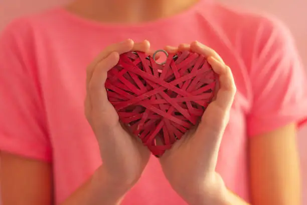 Photo of girl's hands hugging a wicker red heart