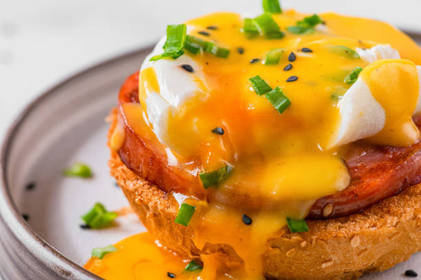 istock Egg benedict. Poached egg, ham, hollandaise sauce, onion on slice toast for tasty breakfast. close up 1366478897