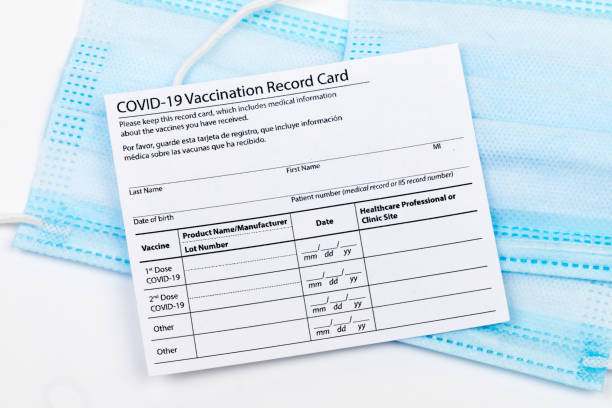 istock Coronavirus vaccination record card. Protective mask divided into two parts. Concept of defeating Covid-19 1366478982